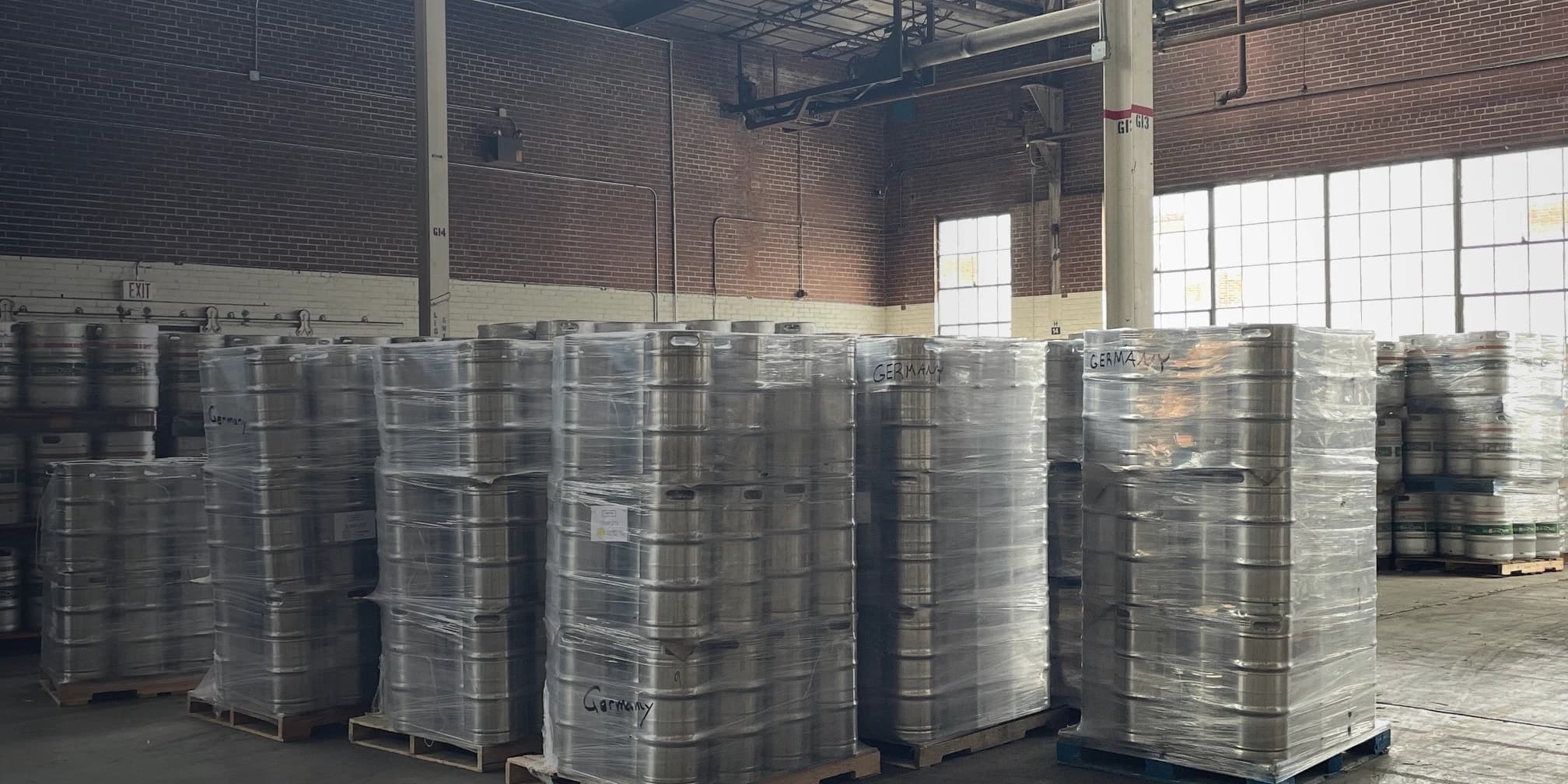 Palletized stainless steel kegs in a brick warehouse